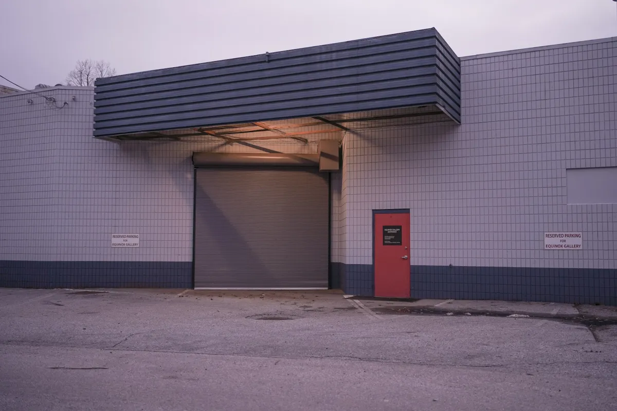 Loading bay with an overhead door under a canopy beside a red service door