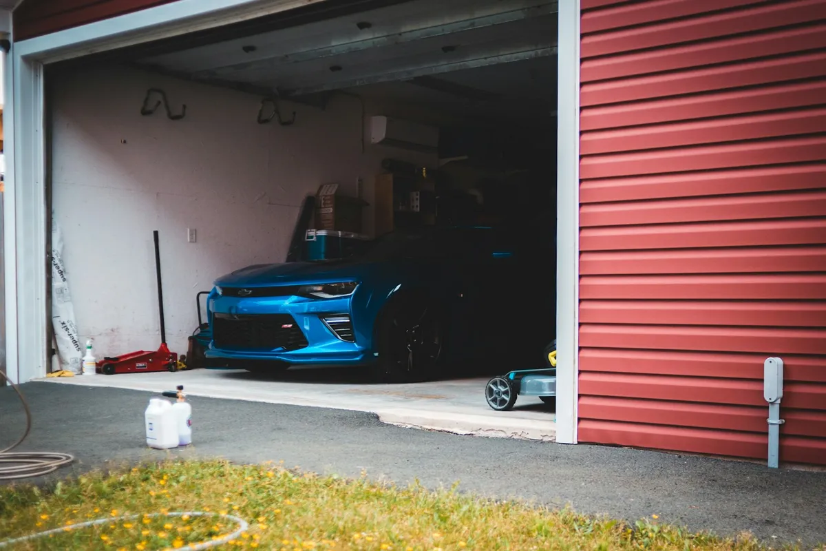 Open garage with a car inside and red siding beside it